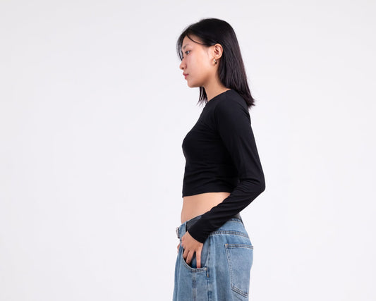 Person wearing a black long-sleeve top and light blue jeans on a white background