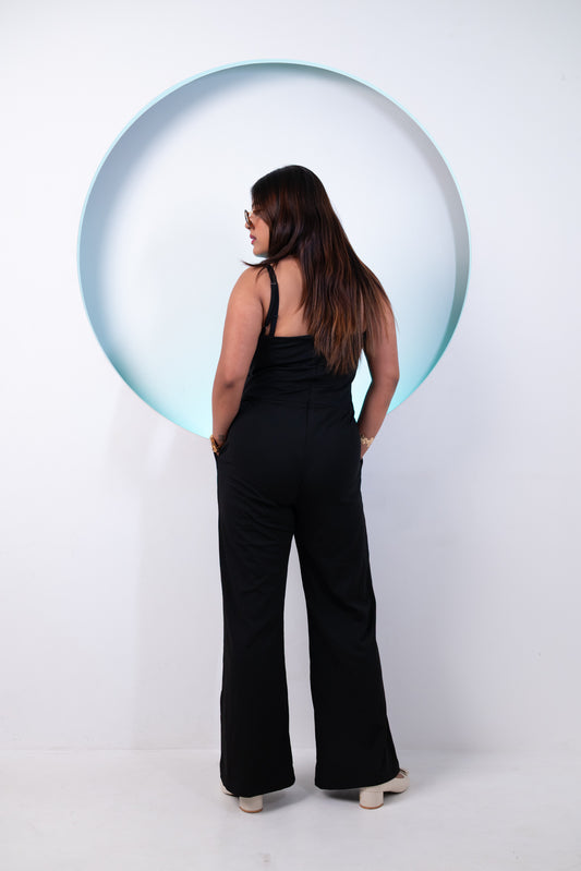 Woman wearing a black jumpsuit standing in front of a large bubble on a white background
