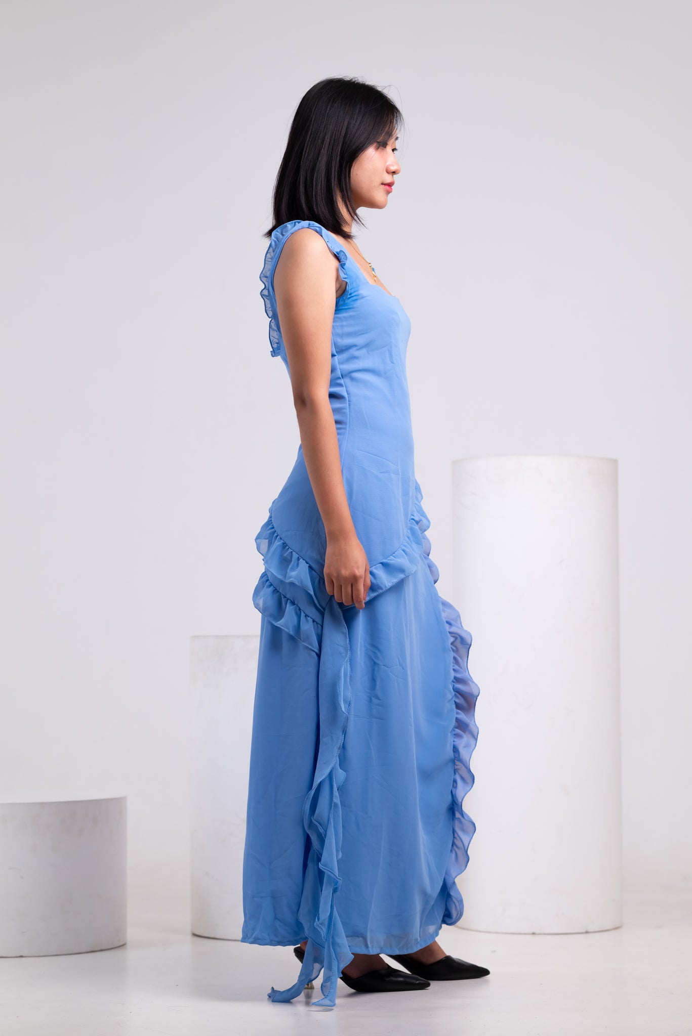 Woman wearing a light blue dress with ruffled details on a white background