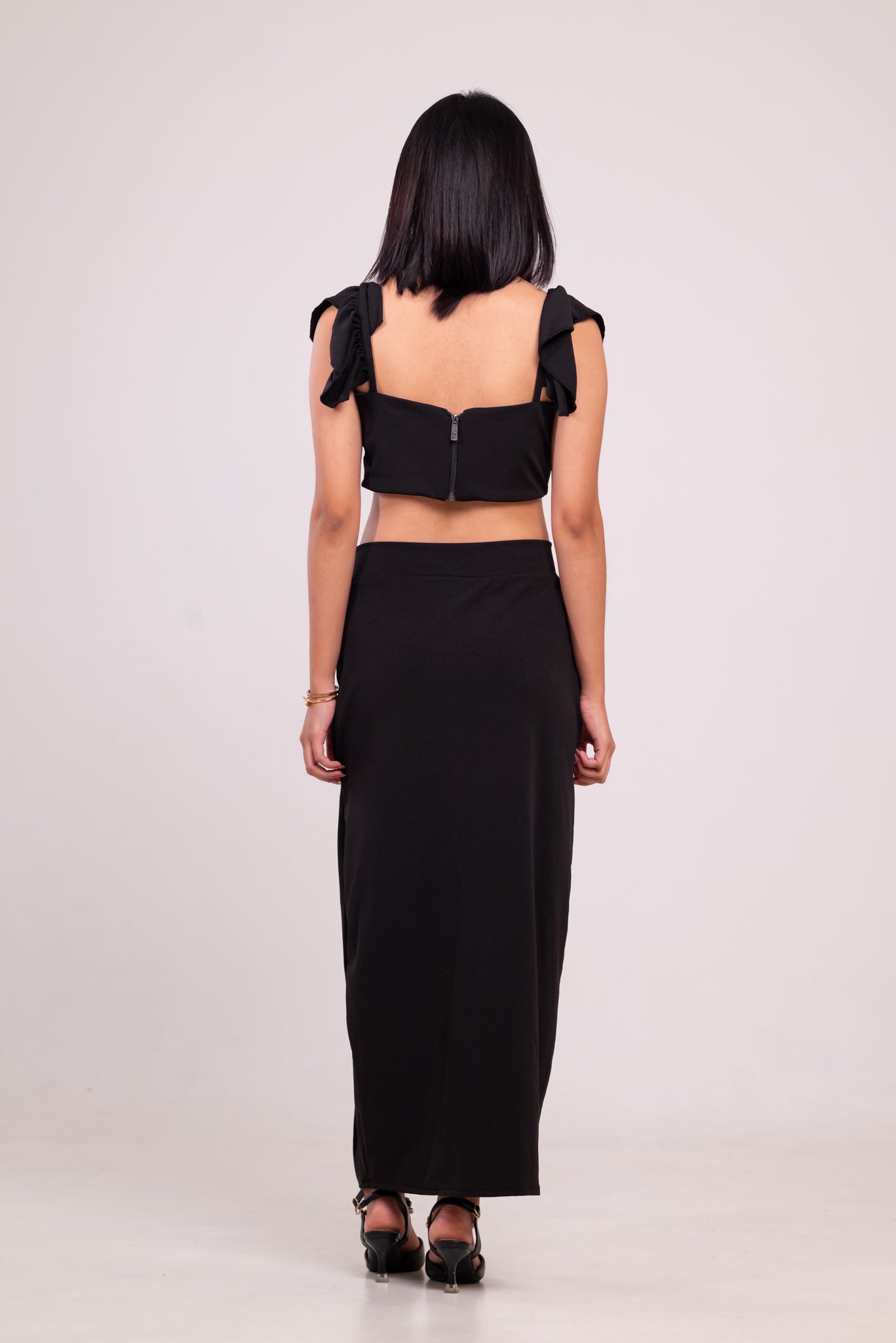 Woman wearing a black outfit with ruffled sleeves on a white background