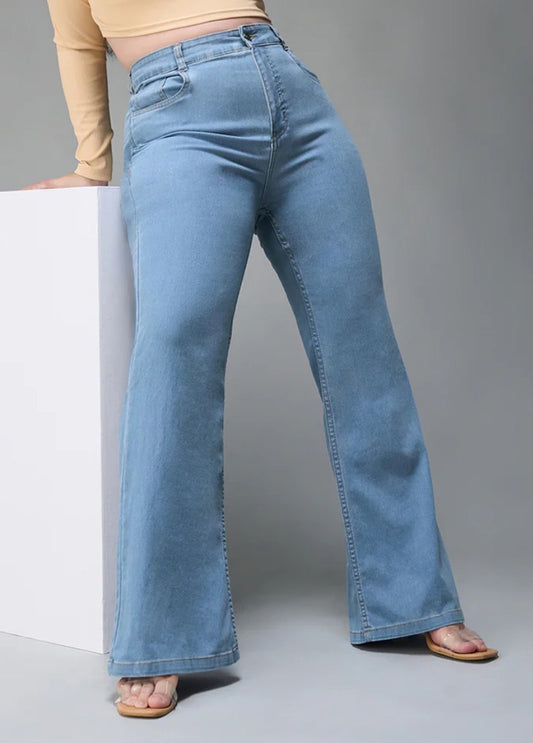 Person wearing light blue flared jeans on a gray background