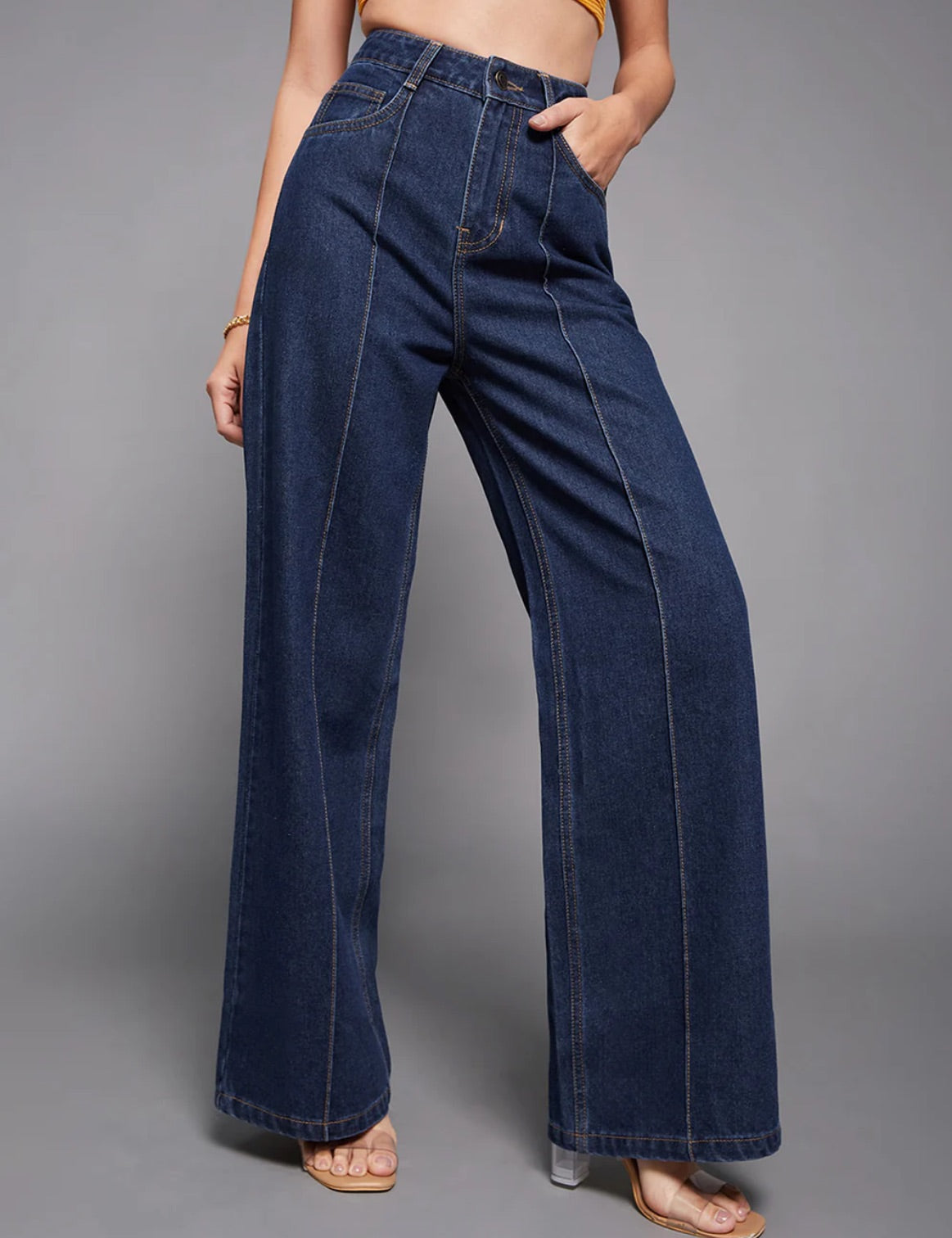 Person wearing wide-leg blue jeans on a gray background