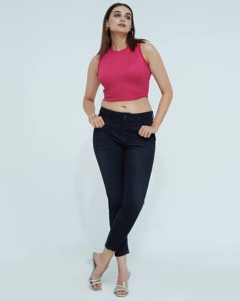 Woman wearing a pink top and black jeans on a white background