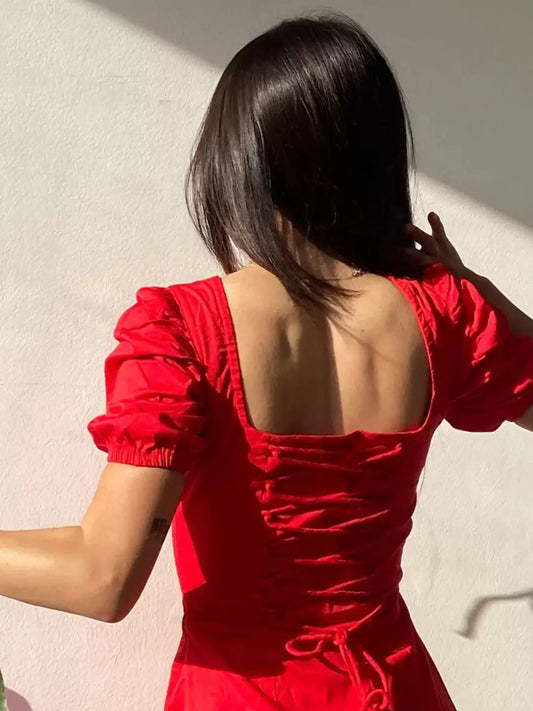 Person wearing a red dress with a backless design against a light background
