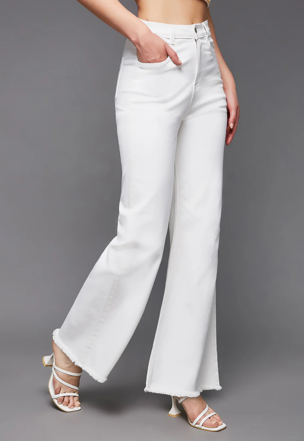 White flared jeans worn by a person on a gray background