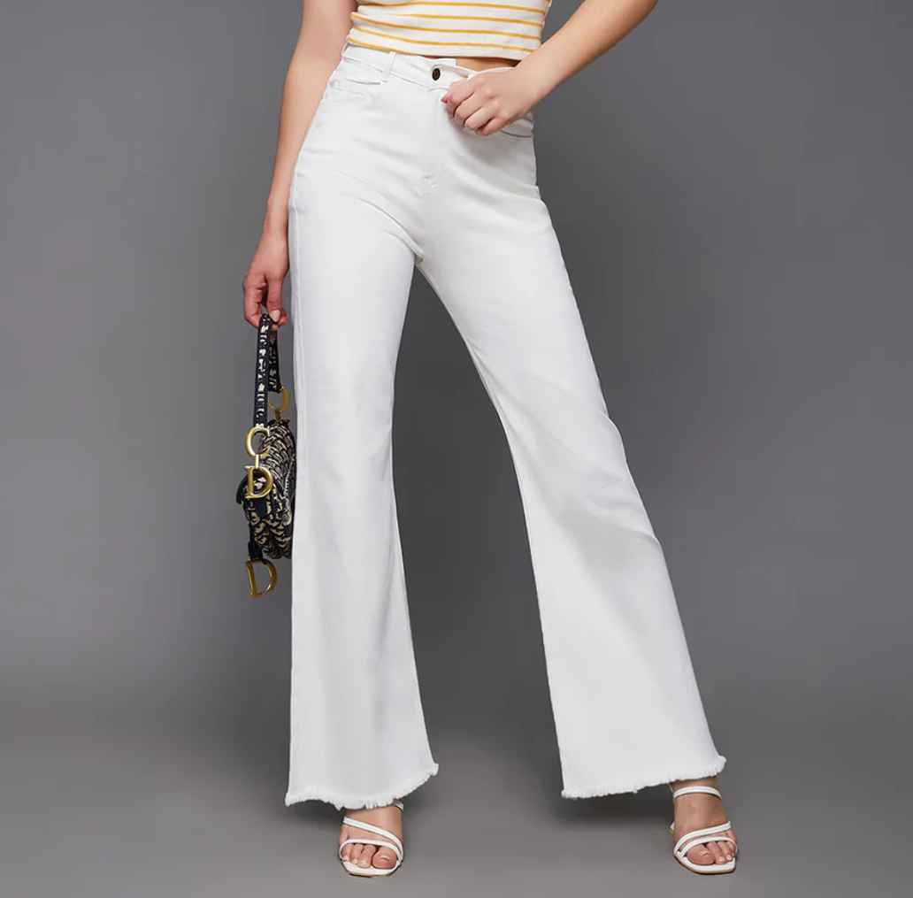Person wearing white flared jeans on a gray background