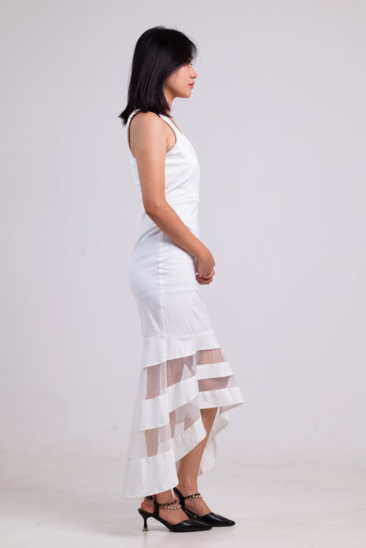 Woman wearing a white dress with sheer overlay on a plain background