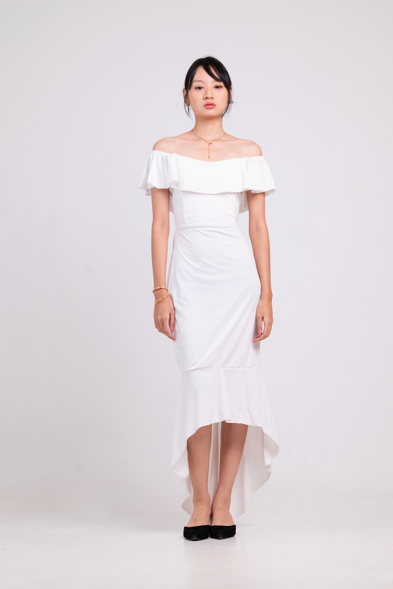 Woman wearing a white off-shoulder dress on a plain background