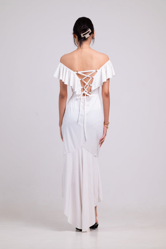 Woman wearing a white off-shoulder dress with ruffled details on a white background