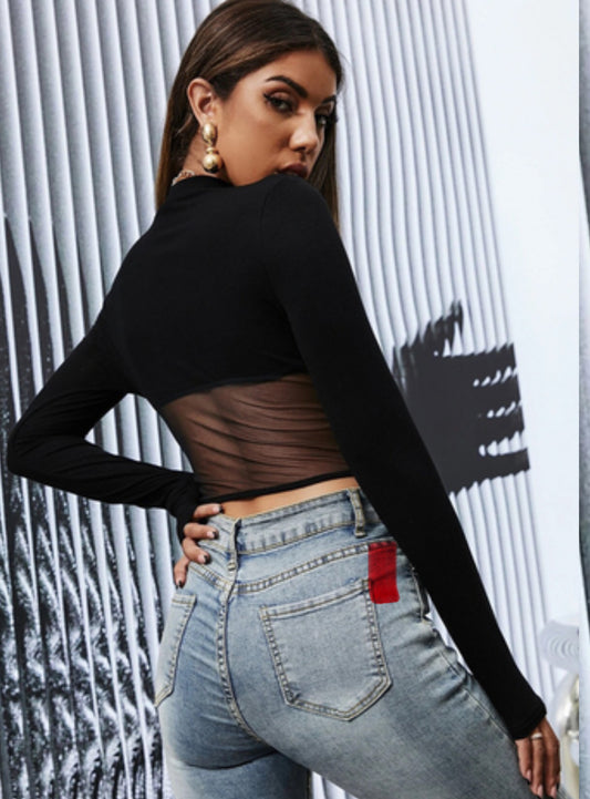 Person wearing a black long-sleeve top and light blue jeans with a red tag.