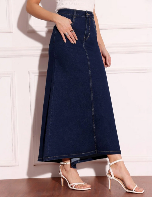 Person wearing a long denim skirt with white sandals on a light background
