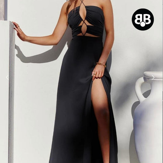 Woman wearing a black evening gown with a high slit, standing against a plain background.