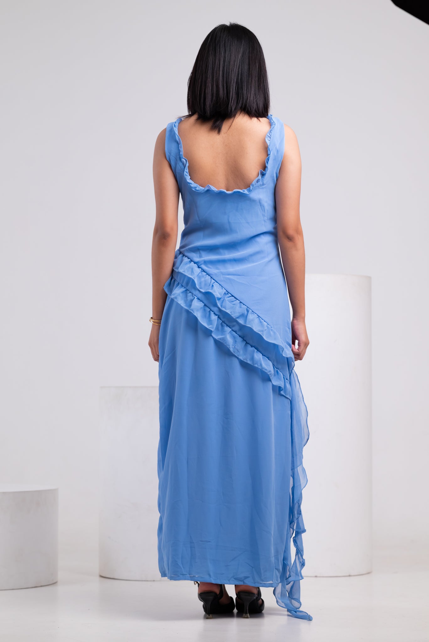 Woman wearing a blue dress with ruffled layers on a white background